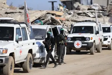 چندین خودرو سفید با صلیب‌های قرمز و دو نفر در لباس نظامی در کنار آن