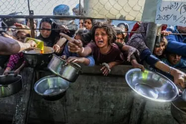 افراد ظرف‌های فلزی را از پشت نرده‌ها می‌گذارند