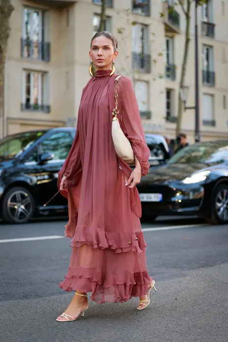 مهمان با پیراهن ماکسی شيفون آلو‌رنگ، گوشواره طلایی، کیف سفید