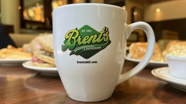 ماگ Brent's Deli روی میزی با غذا